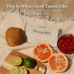 Flat lay of UNTAMMED Mineral Mist Grapefruit Lime electrolyte drink mix pouch on a beach blanket with coconut, grapefruit, limes, and strawberries. Headline: This Is What Clean Tastes Like.